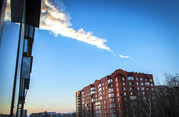 当地时间2013年2月15日,俄罗斯车里雅宾斯克,陨石划过居民楼上空形成的一条白色烟雾。