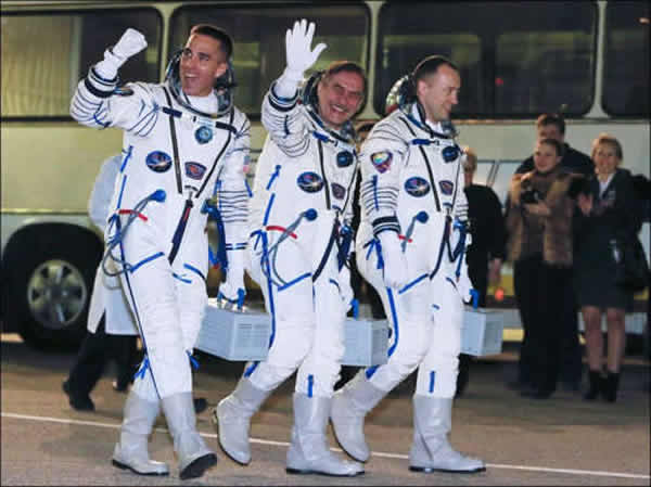 俄宇航员米苏尔金(右)与维诺格拉多夫(中)以及美国宇航员卡西迪前往乘坐飞船。