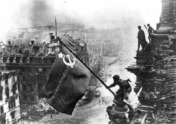 Russian soldiers flying a flag made from table cloths over the ruins of the Reic