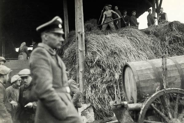 SS guard Schmiller walks past the barn of the Lipa farm labor camp where Jewish