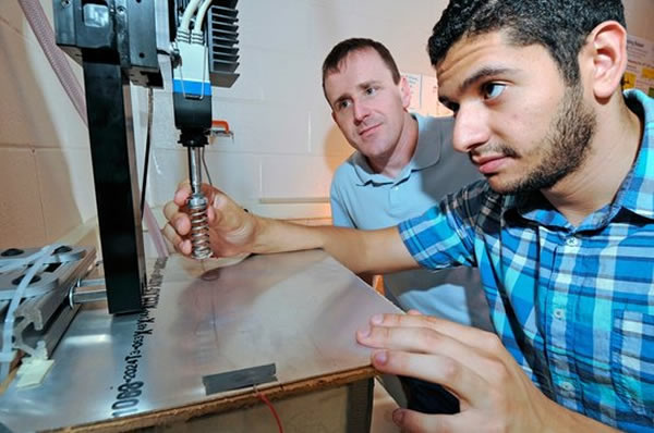 乔治亚理工学院的物理学家丹尼尔-高曼(左)和研究生杰弗里-阿圭勒打造了一个简单的机器人进行跳跃动力学研究。