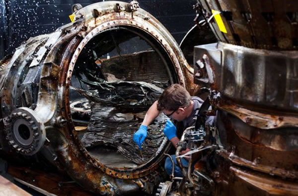 SpaceWorks technician Jerrad Alexander uses a brush to clean an F-1 engine thrus