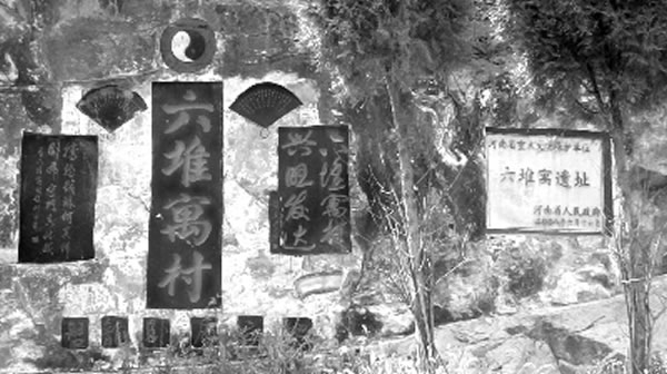 写有河南省重点文物保护单位六堆寓遗址的石碑镶嵌在距东大岭山脚数百米的斜对面山坡上。