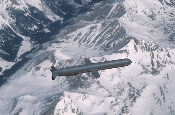 Two U.S. Navy BGM-109C Tomahawk cruise missiles in flight over a mountain range.