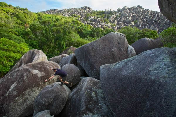 Tropical biologist Conrad Hoskin scrambles over massive boulders looking for rep