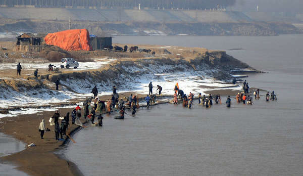 2013年12月18日,济南,放生的市民一走,蜂拥跑到放生的河滩处,或撒开大网捕捞,或是伸着长竹竿渔网捕捞,有的甚至站在齐腰深的水中捕捞。