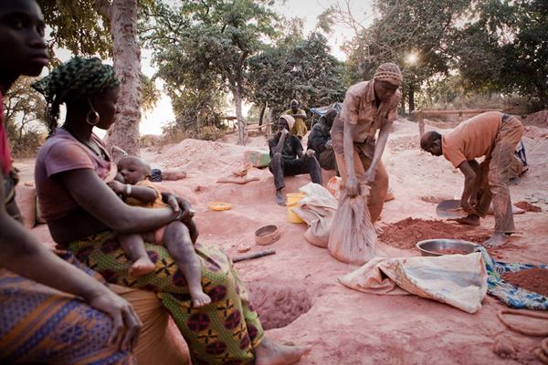 塞内加尔境内一处不受监管的金矿里,男矿工正在淘沙,女矿工正在给孩子喂奶。