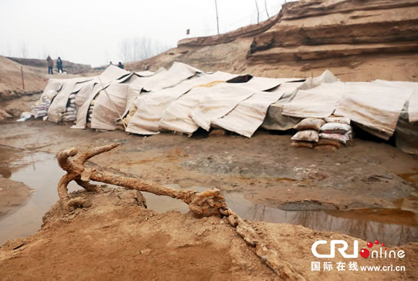 2014年1月6日,河南洛阳古沉船发掘现场,古沉船铁锚从见天日,静静地躺在古船旁。