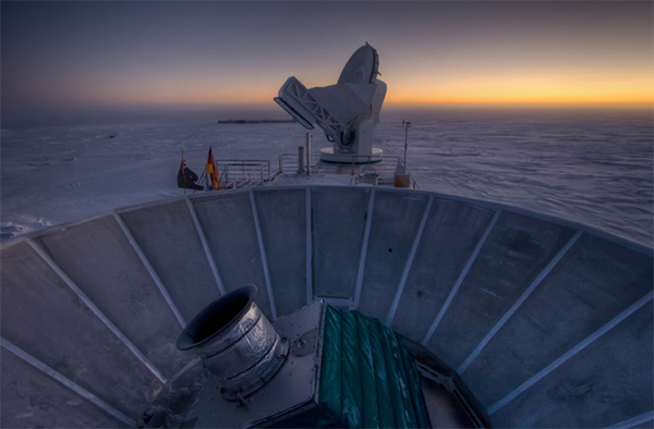 The sun sets behind BICEP2 (in the foreground) and the South Pole Telescope (in
