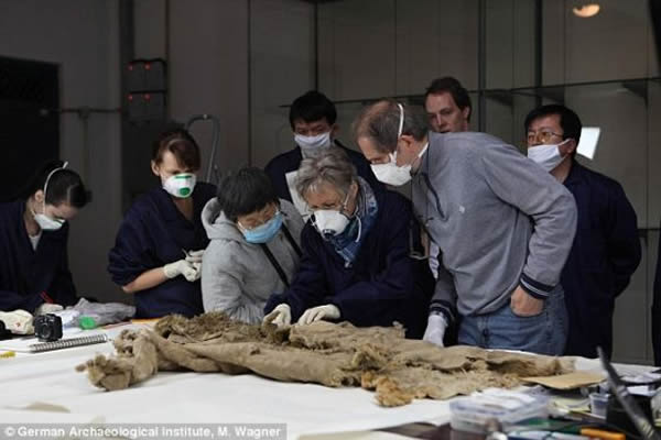 除了裤子外，洋海古墓内还发现其他很多文物，其中包括来自中亚，历史可追溯到3000年前的衣物，每一件都拥有很高的研究价值。照片中，中德科学家正在分析一件皮毛大衣。