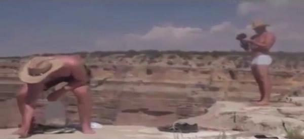 2名游客将面包屑撒在断崖边,准备引诱松鼠上钩。