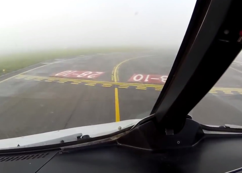 飞机安全降着陆后在跑道上滑行,稍远处视野仍被大雾遮掩。