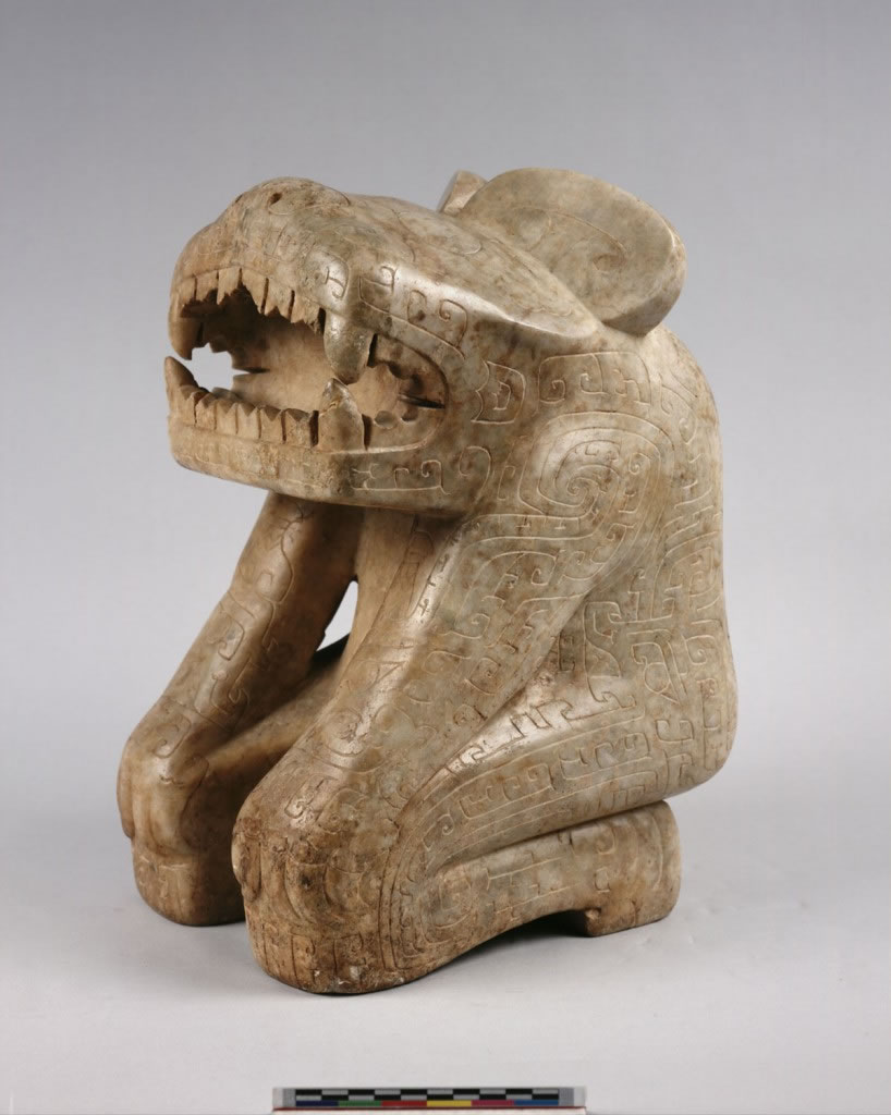 「大理石虎首人身立雕」高37.1公分,重近29公斤,在殷墟出土石雕中最为精美。作屈膝跪坐状,头略上仰,张口露齿,「臣」字眼,扇形耳,手做爪形,置于两膝上。通体饰