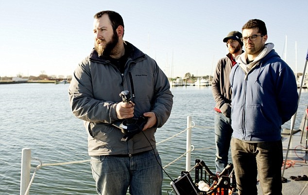 研究员用操控杆,控制机械鱼在水中进行监控任务。