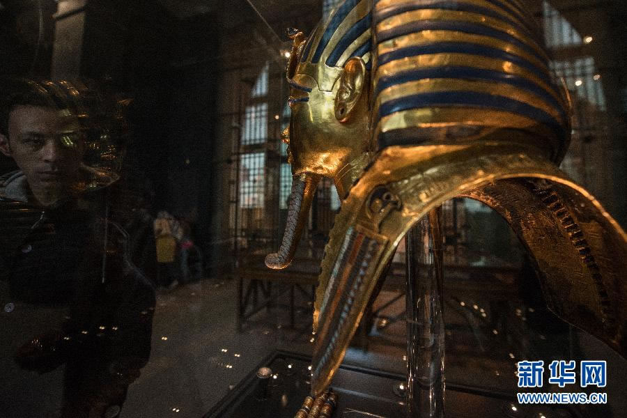 1月23日,在位于开罗的埃及博物馆,一名工作人员透过玻璃柜查看图坦卡蒙黄金面具。