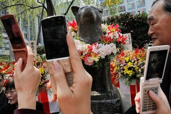 资料图片:游客在东京涉谷站外用手机拍摄“忠犬八公”的雕塑。