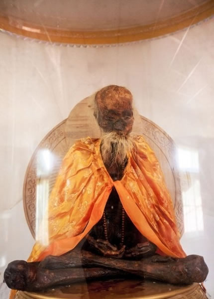 吴云青成跏趺坐姿势,披着金色斗篷,项戴佛珠。