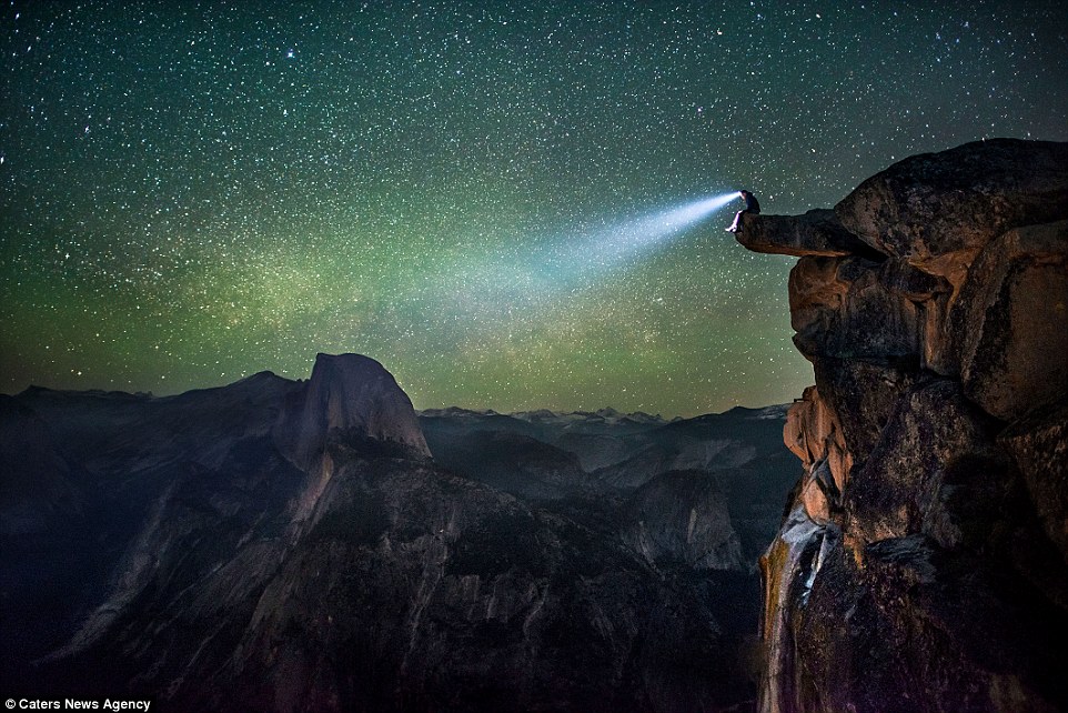 男子头上的照明灯穿过黑暗照亮夜空,点缀着数以千万计的星辰。