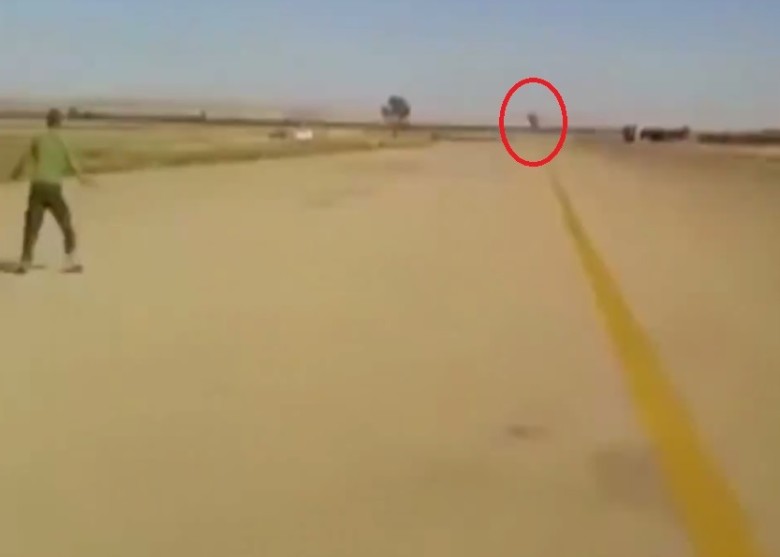 远处传来隆隆巨响,一团黑影(红圈)突然出现,男子似不知何事。