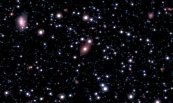 新发现的星系SAGE0536AGN(图像中央粉色椭圆星系)被发现其中心存在一个超大质量黑洞,并且其质量远超天文学家们的预期。这个黑洞的成长速度似乎远远超出了它的