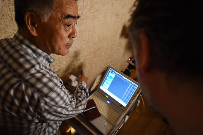 渡边广胜一边指着墓壁一边与瑞福斯讨论雷达扫描状况。 PHOTOGRAPH BY BRANDO QUILICI, NATIONAL GEOGRAPHIC CHAN