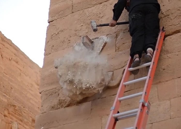 IS分子爬上长梯,手持重锤不断敲打伊拉克古城雕像。