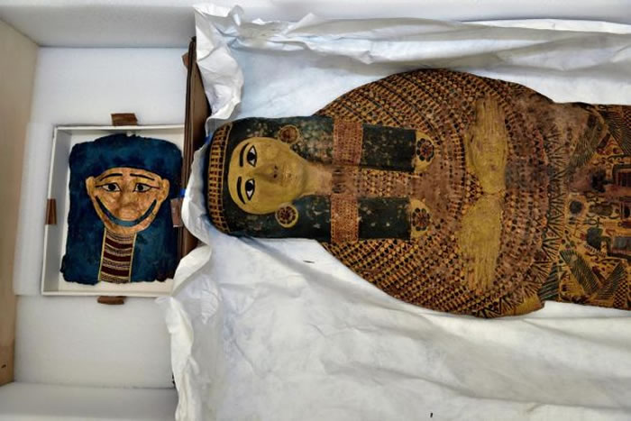 一枚埃及镀金木乃伊面具(左)放在棺木旁。这两件骨董皆被非法偷渡到美国,并即将运回目前兴建中的大埃及博物馆。 PHOTOGRAPH BY KENNETH GARR