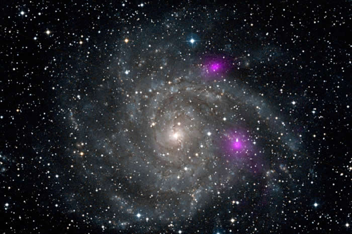 紫红色斑点是螺旋星系旋臂上的小型黑洞所发射出的明亮X射线。 / PHOTOGRAPH BY NASA, JPL-CALTECH, DSS
