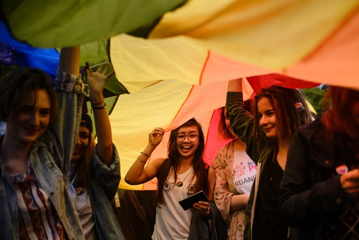 众女郎举起巨型彩虹旗游行。