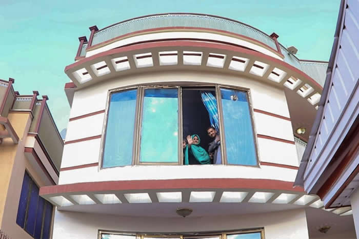 夏帕特.古拉从新家的窗户向外挥手。阿富汗政府为她的家庭支付房租与生活费。 COURTESY ADMINISTRATIVE OFFICE OF THE PRESI