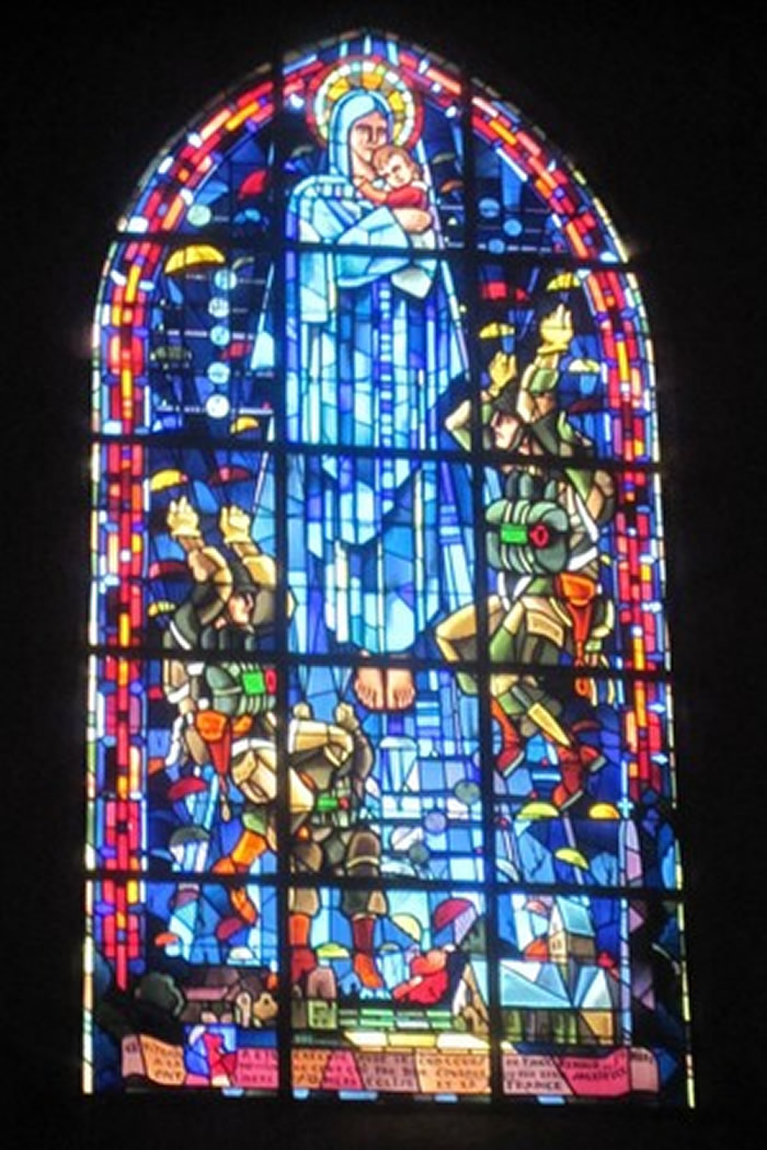 教堂彩绘玻璃描绘伞兵降落于圣母玛莉亚面前,其中一人便是约翰。