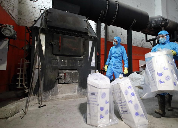 乌克兰基辅的工人将用过的医疗口罩和手套丢进焚化炉烧掉。 PHOTOGRAPH BY VOLODYMYR TARASOV, UKRINFORM/BARCROFT